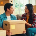Couple discute assis sur canapé, boites en carton prêtes au déménagement