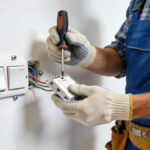 Electricien fixant un interrupteur double dans un mur blanc