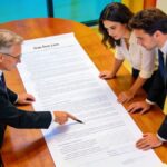 Notaire et couple examinant contrat immobilier longue duree sur grande table