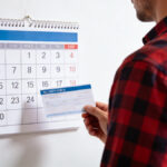 Proprietaire tenant un cheque de caution devant un calendrier mural