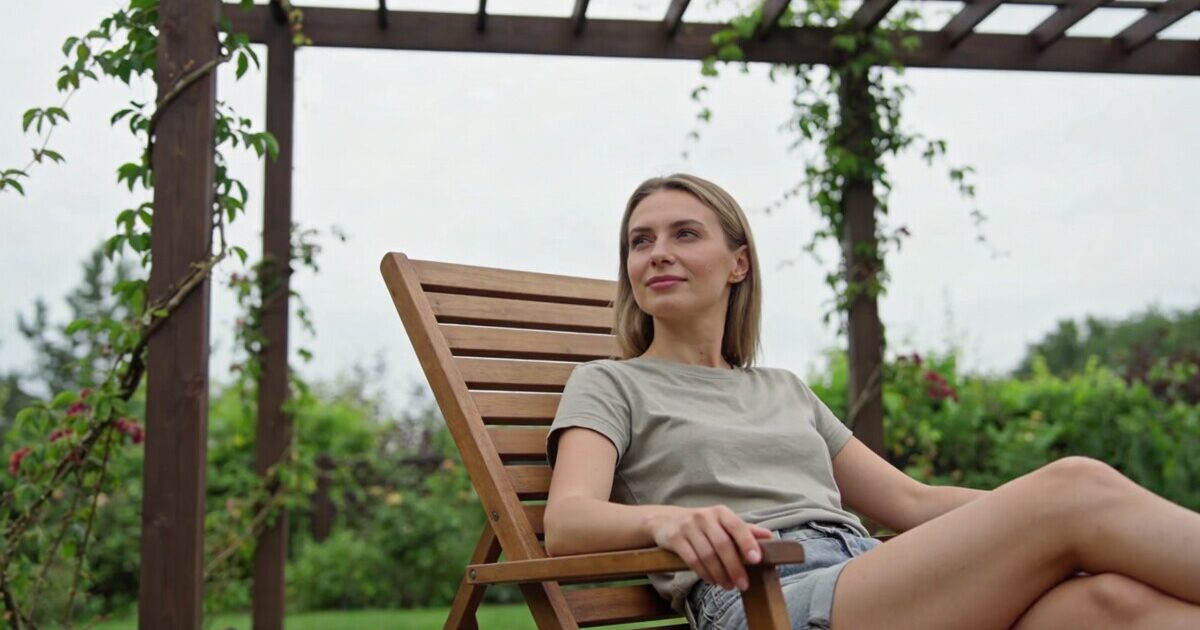 femme assise sur transat bois sous pergola jardin