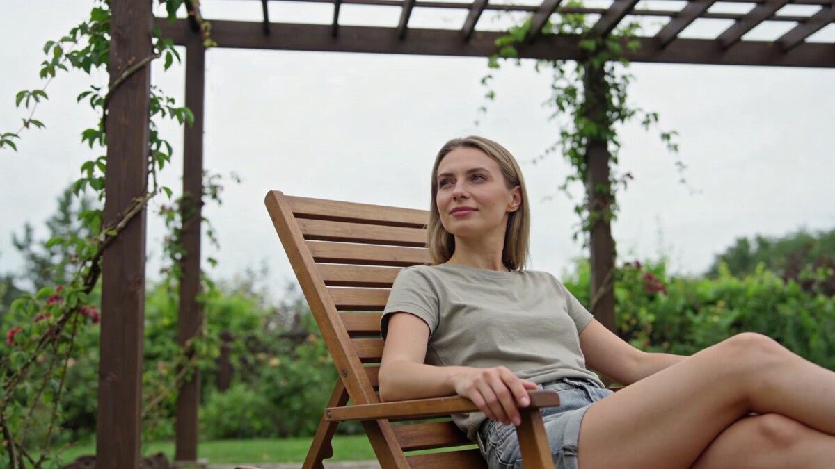 femme assise sur transat bois sous pergola jardin