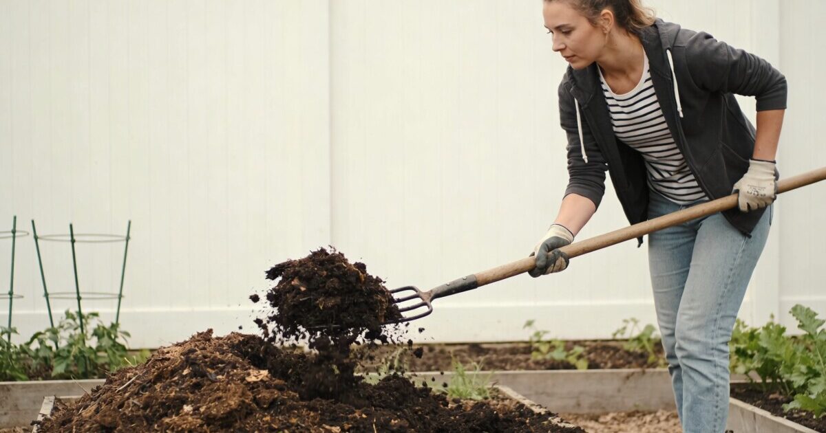 Femme retournant un tas de compost au jardin