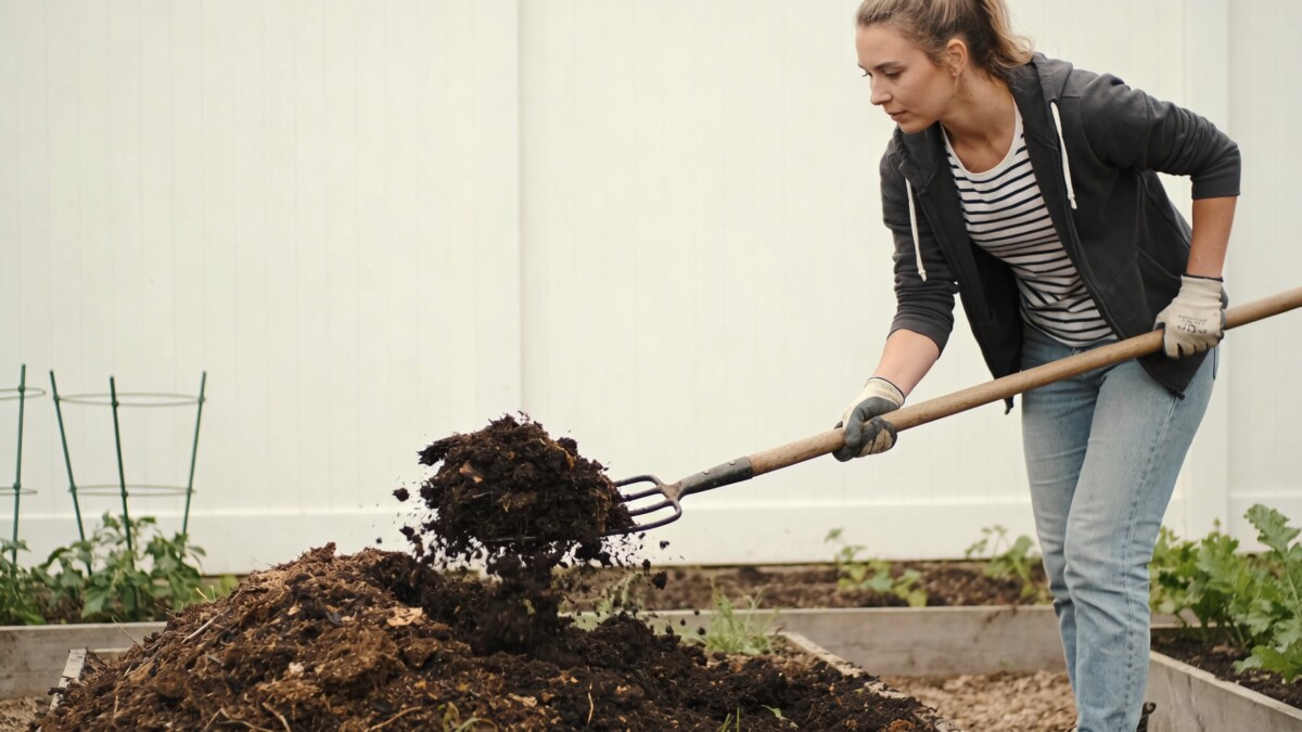 Femme retournant un tas de compost au jardin