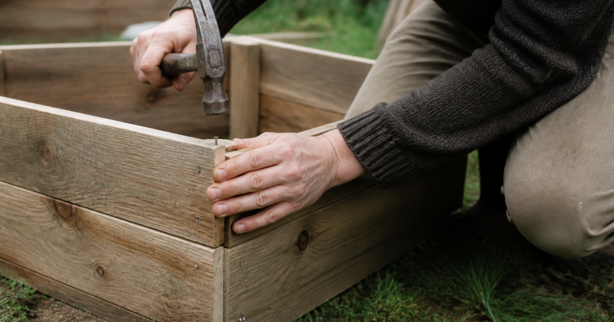 Mains assemblant planches bois clouees pour bac plantes